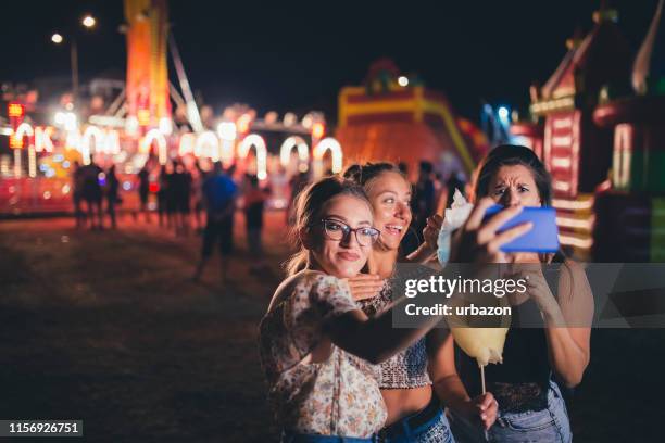 mädchen, die selfies mit zuckerwatte machen - fairgrounds festival 2017 stock-fotos und bilder