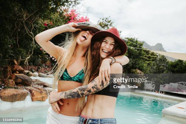 two happy girlfiriends embrace at poolside - friends smile stock-fotos und bilder