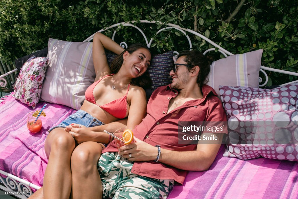 Young couple lounging in the sun on an outdoor sofa