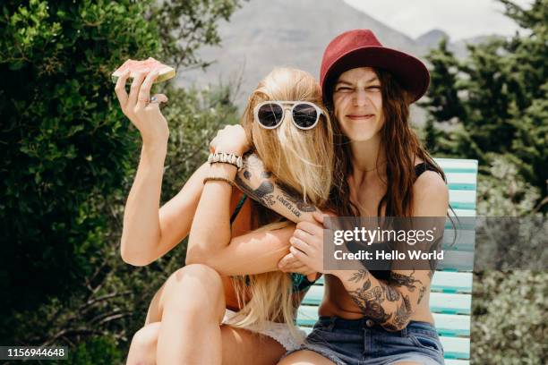 happy oddball girlfriends embrace outdoors with watermelon in hand - diversión fotografías e imágenes de stock