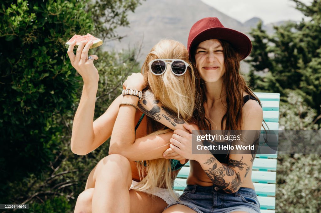 Happy oddball girlfriends embrace outdoors with watermelon in hand