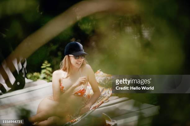 young bikini clad woman spotted chatting at poolside through leaves - see through swimsuit ストックフォトと画像