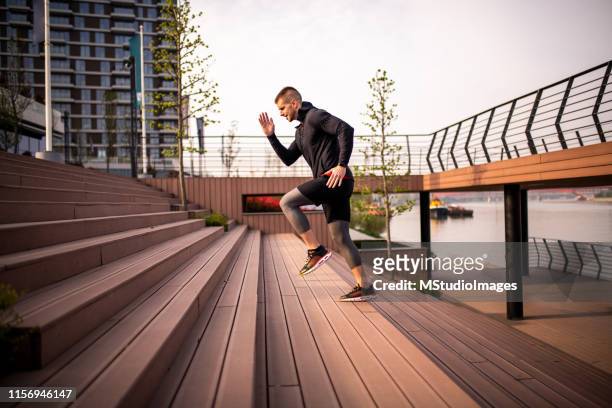 side view on a sporty man running upstairs - running man profile stock pictures, royalty-free photos & images