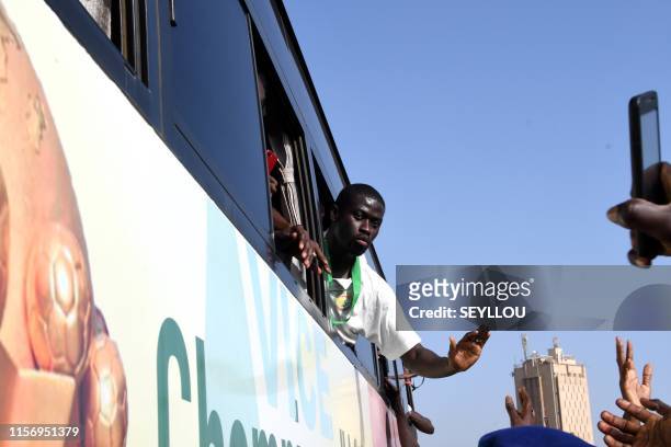 Senegal's midfielder Papa Alioune N'Diaye waves to supporters from a window of a bus in Dakar on July 20, 2019 a day after losing the 2019 Africa Cup...