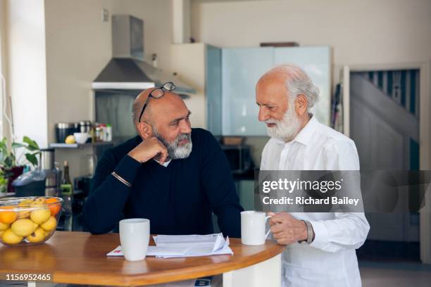 elderly sikh man with son in kitchen. - richard gentles stock pictures, royalty-free photos & images