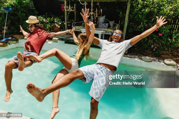 three fully clothed friends falling backwards into pool - pool party fotografías e imágenes de stock