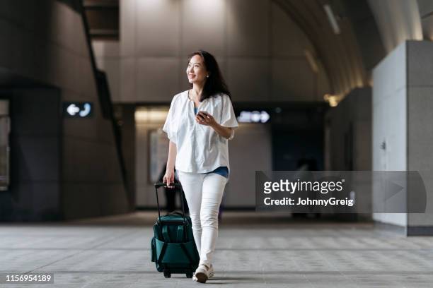 kinesisk kvinna på station med hjulförsedda res väska - asian tourist bildbanksfoton och bilder