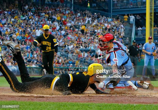 Joe Musgrove of the Pittsburgh Pirates scores on a RBI single in the third inning against J.T. Realmuto of the Philadelphia Phillies at PNC Park on...