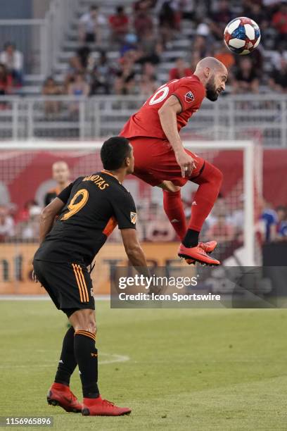 Toronto FC Defender Laurent Ciman heads the ball as Houston Dynamo Forward Mauro Manotas looks on during the regular season MLS soccer match between...