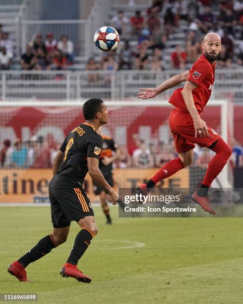 Toronto FC Defender Laurent Ciman heads the ball as Houston Dynamo Forward Mauro Manotas looks on during the regular season MLS soccer match between...