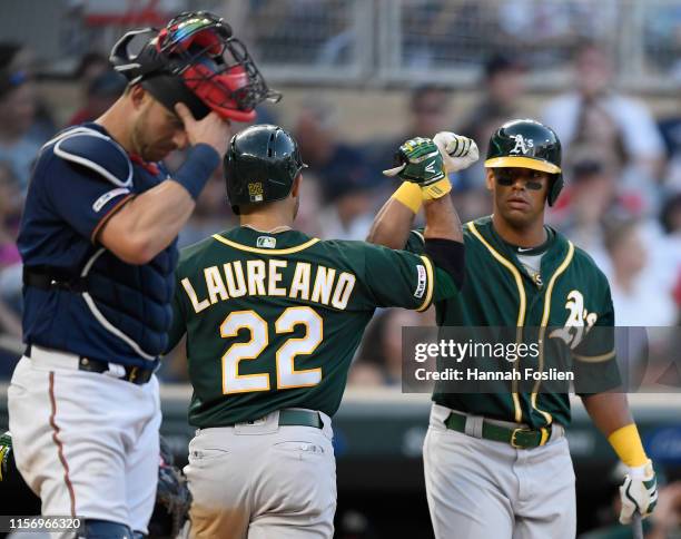 Mitch Garver of the Minnesota Twins looks on as Khris Davis of the Oakland Athletics congratulates teammate Ramon Laureano on a solo home run during...