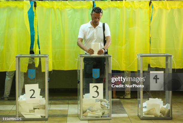 Man throws her ballot into the polling box at the station during the parliamentary elections in Kiev, Ukraine, 21 July 2019. Ukraine votes for the...