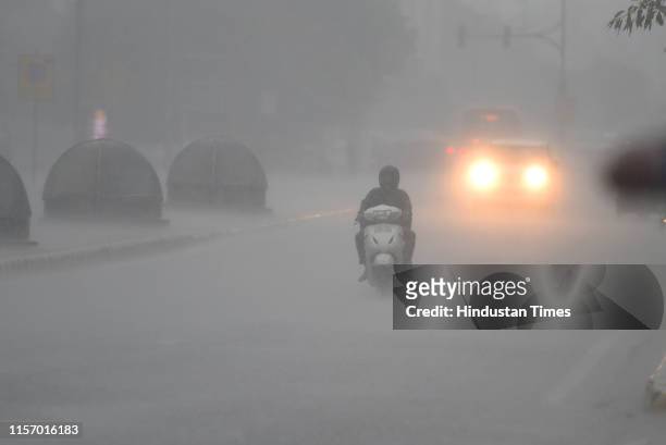 Commuters use lights during heavy rainfall, at Barakhamba Road, on July 21, 2019 in New Delhi, India. The minimum temperature was recorded at 28.8...