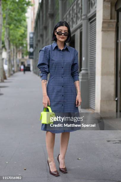 Guest is seen on the street attending Men's Paris Fashion Week wearing navy dress with neon Off-White bag on June 19, 2019 in Paris, France.