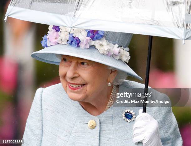 Queen Elizabeth II shelters under an umbrella as she attends day two of Royal Ascot at Ascot Racecourse on June 19, 2019 in Ascot, England.