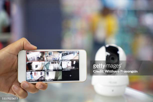 a person's hand holding mobile phone with cctv camera footage on screen - surveillance camera stockfoto's en -beelden