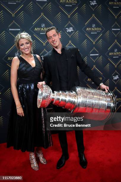 Jordan Binnington of the St. Louis Blues and guest stand alongside the Stanley Cup as he arrives at the 2019 NHL Awards at the Mandalay Bay Events...