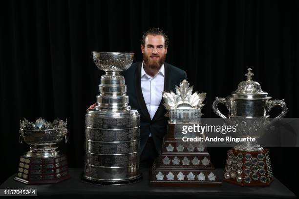 Ryan O'Reilly of the St. Louis Blues poses for a portrait with the Frank J. Selke Trophy, Stanley Cup, Conn Smythe Trophy and the Clarence S....