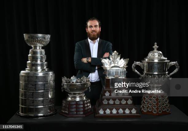 Ryan O'Reilly of the St. Louis Blues poses for a portrait with the Stanley Cup, Frank J. Selke Trophy, Conn Smythe Trophy and the Clarence S....