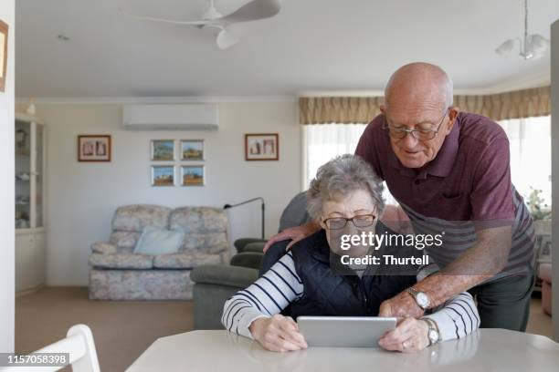 senior australian paar lernen, digitales tablet zu verwenden - social security stock-fotos und bilder