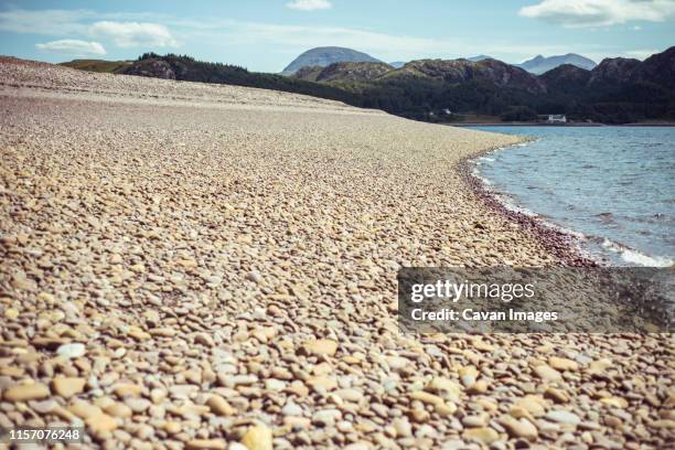 beautiful pebbled beach on remote island with mountains in scotland - pebbled road stock pictures, royalty-free photos & images