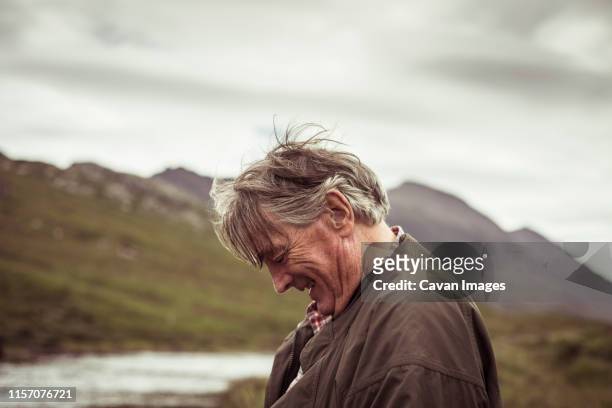 retired man laughs and smiles out fishing in remote river mountian - grandfather silhouette stockfoto's en -beelden