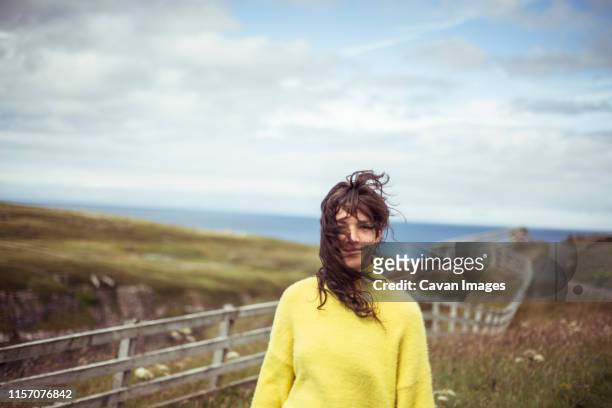 wild hair blows in girls face on remote coastline - tousled hair man stock pictures, royalty-free photos & images
