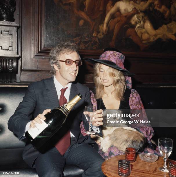 British comedian and actor Peter Sellers pouring a glass of champagne as he sits beside his wife, Australian fashion model Miranda Quarry, at the...