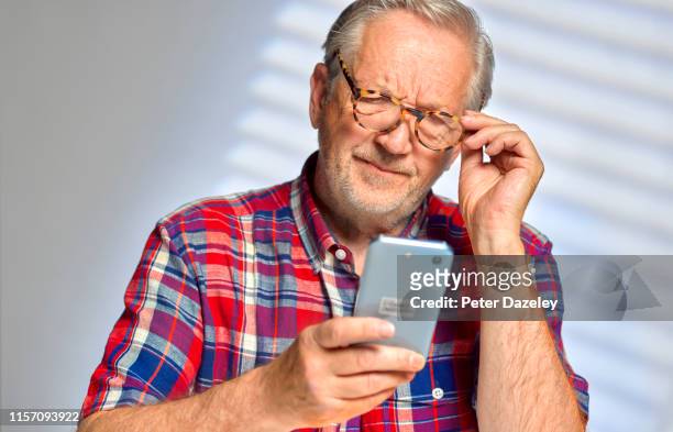 senior man staring at his smart phone in confusion - webshopper stock-fotos und bilder
