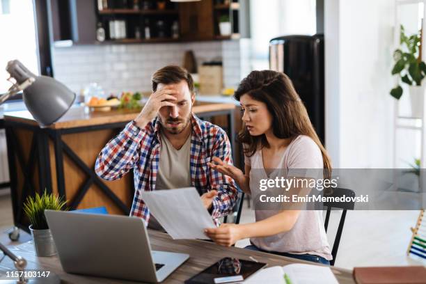 frustrated couple checking bills at home using laptop - couples fighting money stock pictures, royalty-free photos & images