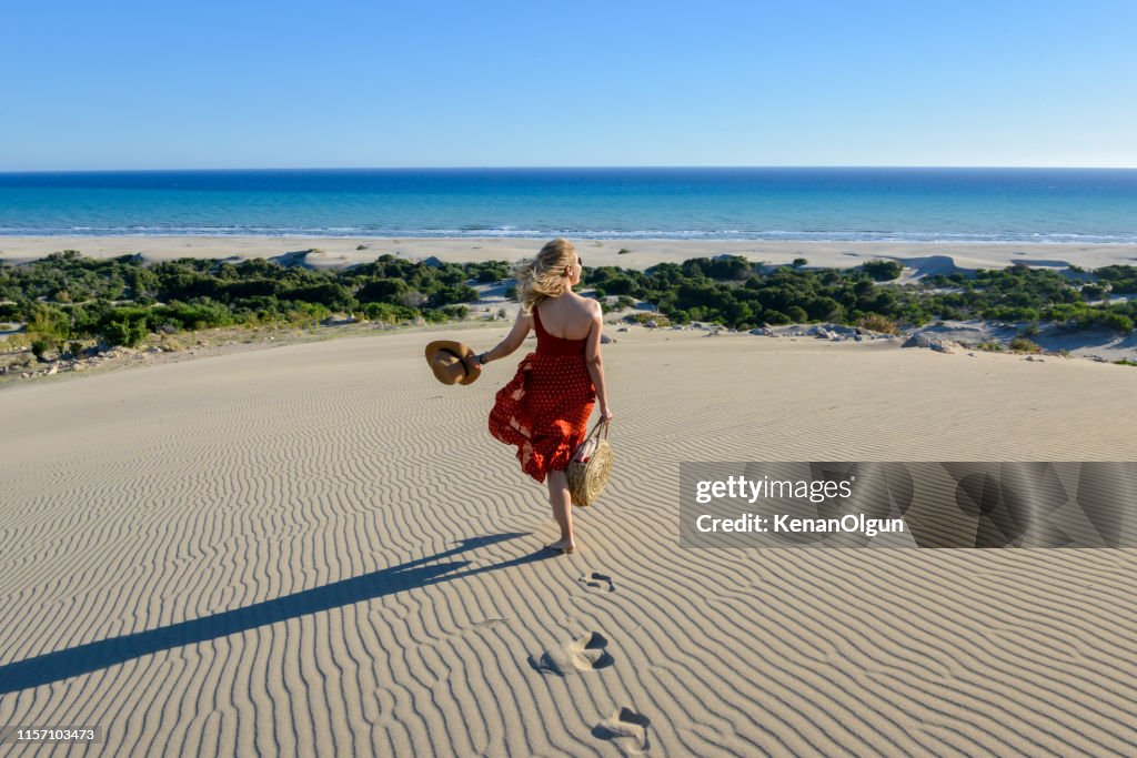 Woman on the sand goes to the sea on foot.