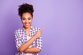 Portrait of her she nice charming cute attractive lovely cheerful wavy-haired girl in checked shirt showing aside ad advert product copy space isolated over violet purple pastel background
