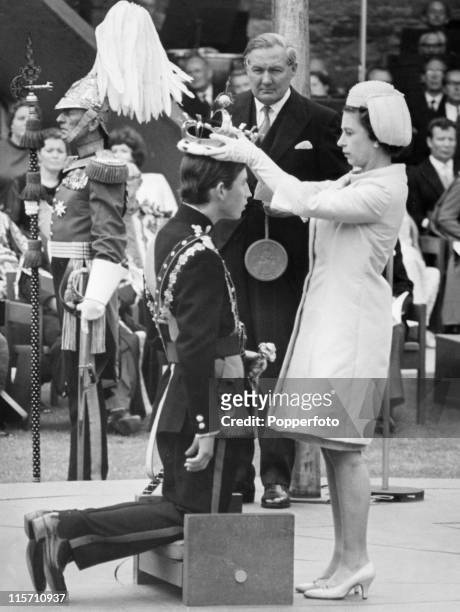 Queen Elizabeth II places the coronet on the head of her son Prince Charles during his investiture as Prince of Wales at Caernarvon Castle on 1st...