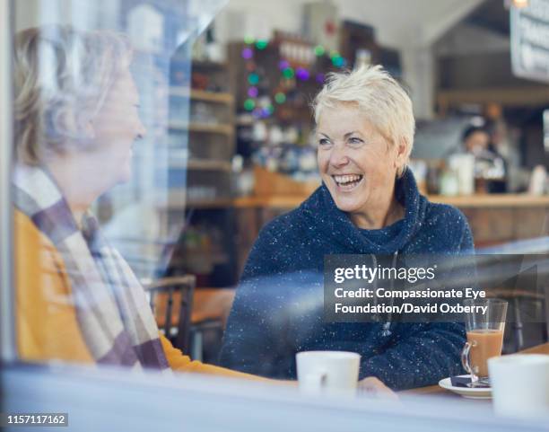 smiling lesbian couple drinking coffee and talking in cafe - couple short hair stock pictures, royalty-free photos & images