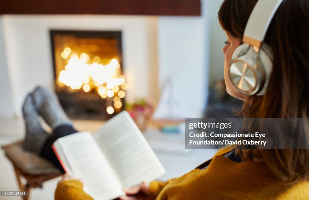 Woman with headphones reading in living room