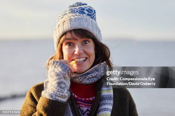 smiling woman eating fries by sea - david swallow stock pictures, royalty-free photos & images