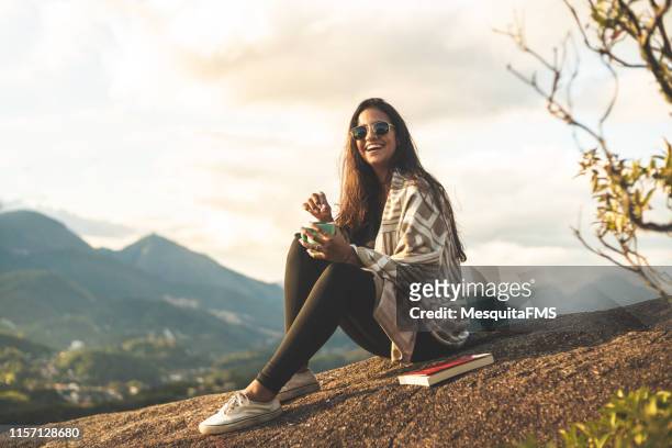 jonge vrouw lezen en drinken van koffie in de bergen (pedra do cortiço) in de serra dos orgãos national park, rio de janeiro, brazilië - book top view stockfoto's en -beelden