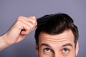 Cropped close up photo amazing he him his macho hands arms plastic hair styling brush take care hairdo barber shop stylist visit look up process experiment wear white t-shirt isolated grey background