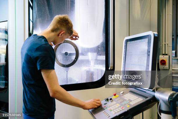 industry 4.0: young engineer looks into the monitor of a cnc machine - industry 4 0 imagens e fotografias de stock