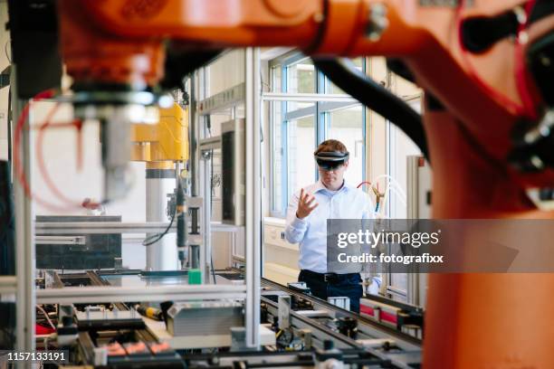 engineer works with a hololens: place a virtual robotic arm into the production line - cam imagens e fotografias de stock