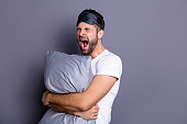 Portrait of his he nice-looking attractive exhausted sleepy bearded guy holding in hands pillow drowsiness going to bed isolated over gray pastel violet purple background