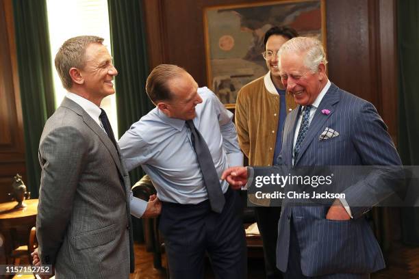 Prince Charles, Prince of Wales speaks to actors Daniel Craig, Ralph Fiennes and director Cary Joji Fukunaga during a visit to the James Bond set at...