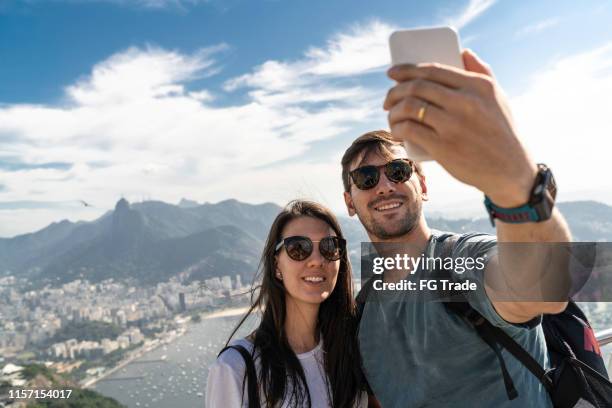 tourist couple taking a selfie in rio de janeiro using a phone - tourism in brazil stock pictures, royalty-free photos & images