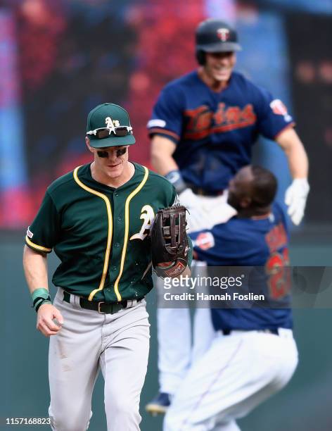 Mark Canha of the Oakland Athletics leaves the field as Miguel Sano of the Minnesota Twins congratulates teammate Max Kepler on a walk-off single...