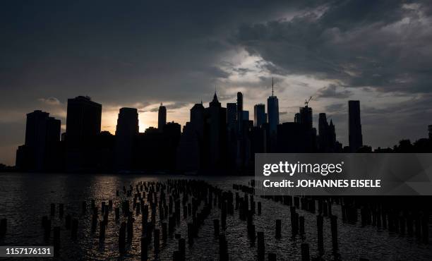 The sun sets behind the skyline of Lower Manhattan on July 21, 2019 in New York City. - The United States sweltered in dangerously hot weather on...