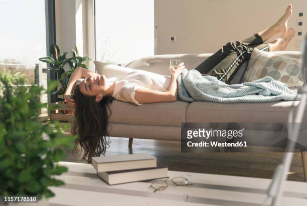 relaxed young woman lying on couch - comodità foto e immagini stock