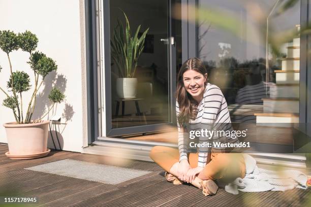 portrait of laughing young woman sitting on terrace at home - sitting on floor stock pictures, royalty-free photos & images