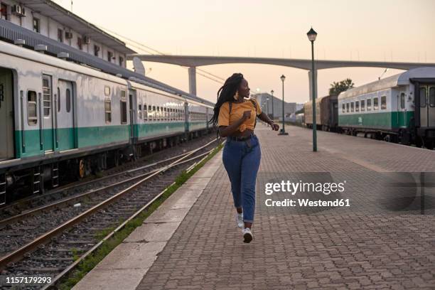 young woman running on platform at the train station - railroad station platform stockfoto's en -beelden