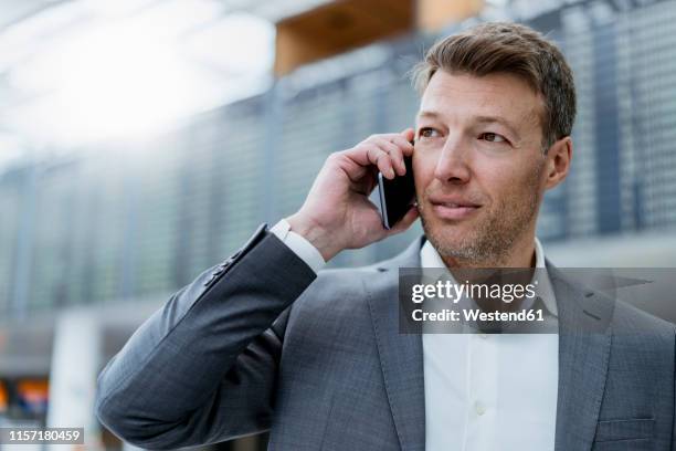 portrait of businessman on cell phone at the airport - departure board front on fotografías e imágenes de stock