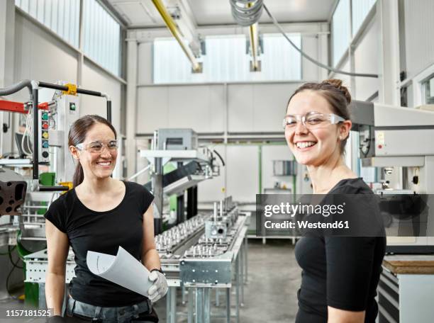two woman working on a machine - fun experience stock-fotos und bilder